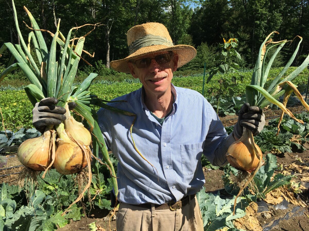 Farmer Knisely holding an abundant amount of onions