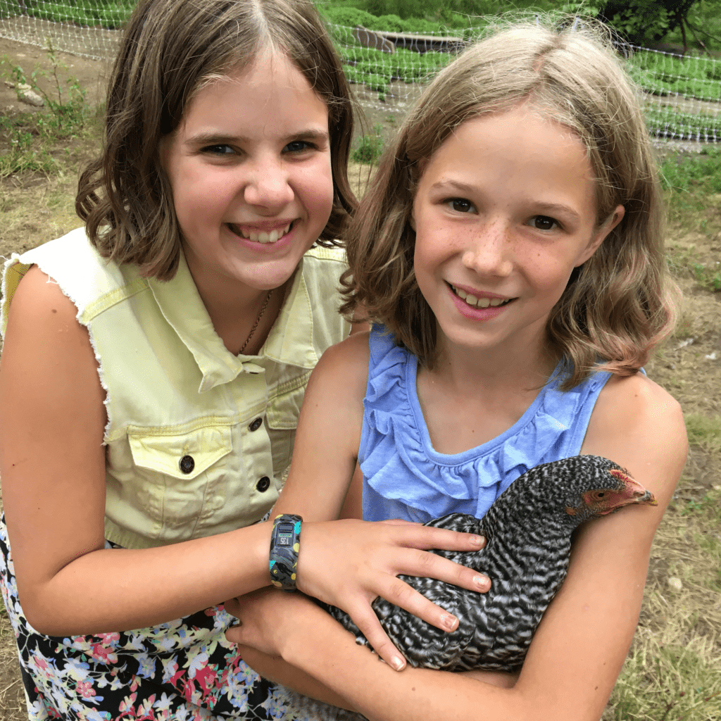 Two young girls holding a chicken